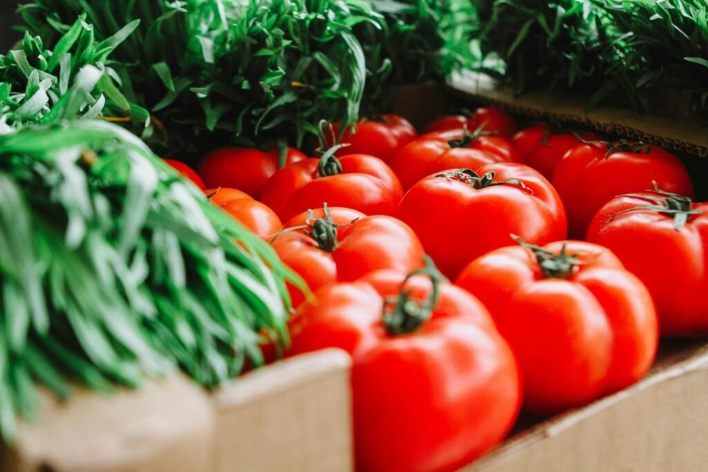 Contactar Alimentacion Amarilla - Vibrant red tomatoes and fresh greens displayed at a London farmer's market, showcasing organic produce.